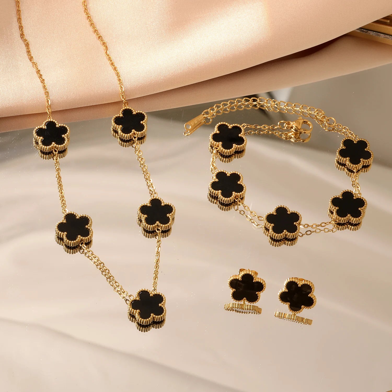 Gold-tone clover jewelry set with black enamel necklace, bracelet, and stud earrings