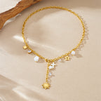 Gold-tone charm necklace with star and cross pendants, pearl beads, and sun charm