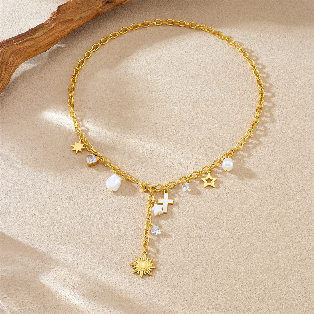 Gold-tone charm necklace with star and cross pendants, pearl beads, and sun charm