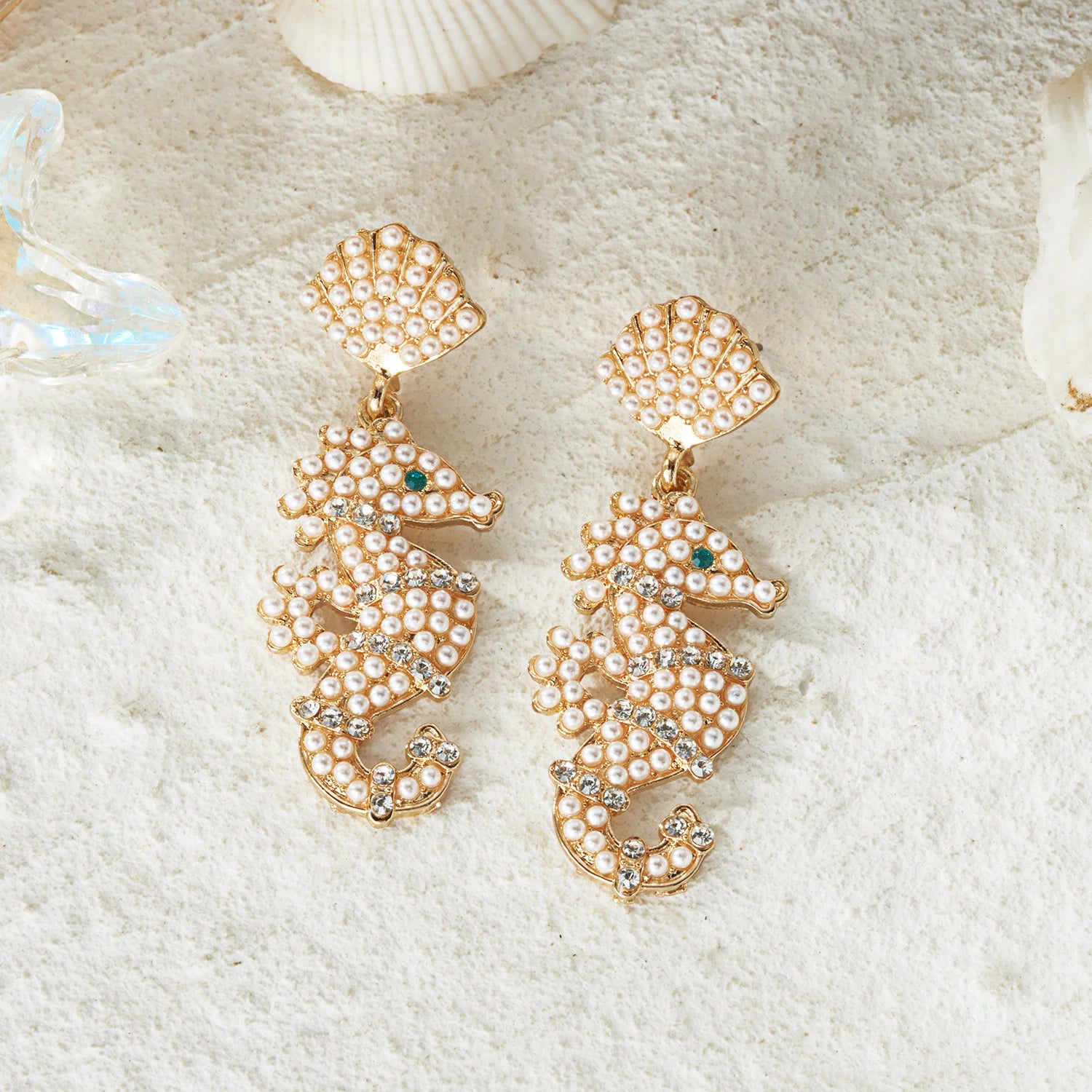 Gold-tone pearl shell earrings with teardrop tops and green jewel accents