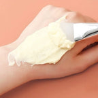 Silicone face mask brush applying pale cream, with white silicone head and chrome ferrule