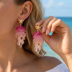 Gold starfish drop earrings with pink jellyfish charms and translucent tentacles.