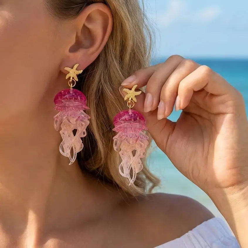 Gold starfish drop earrings with pink jellyfish charms and translucent tentacles.