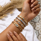 Gold plated bangle set with blue evil-eye charms, worn on the wrist