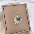 Gold-tone heartlike pendant necklace with blue oval gemstone and rhinestone border