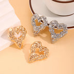 Heart-shaped drop earrings in gold and silver with ornate raised texture