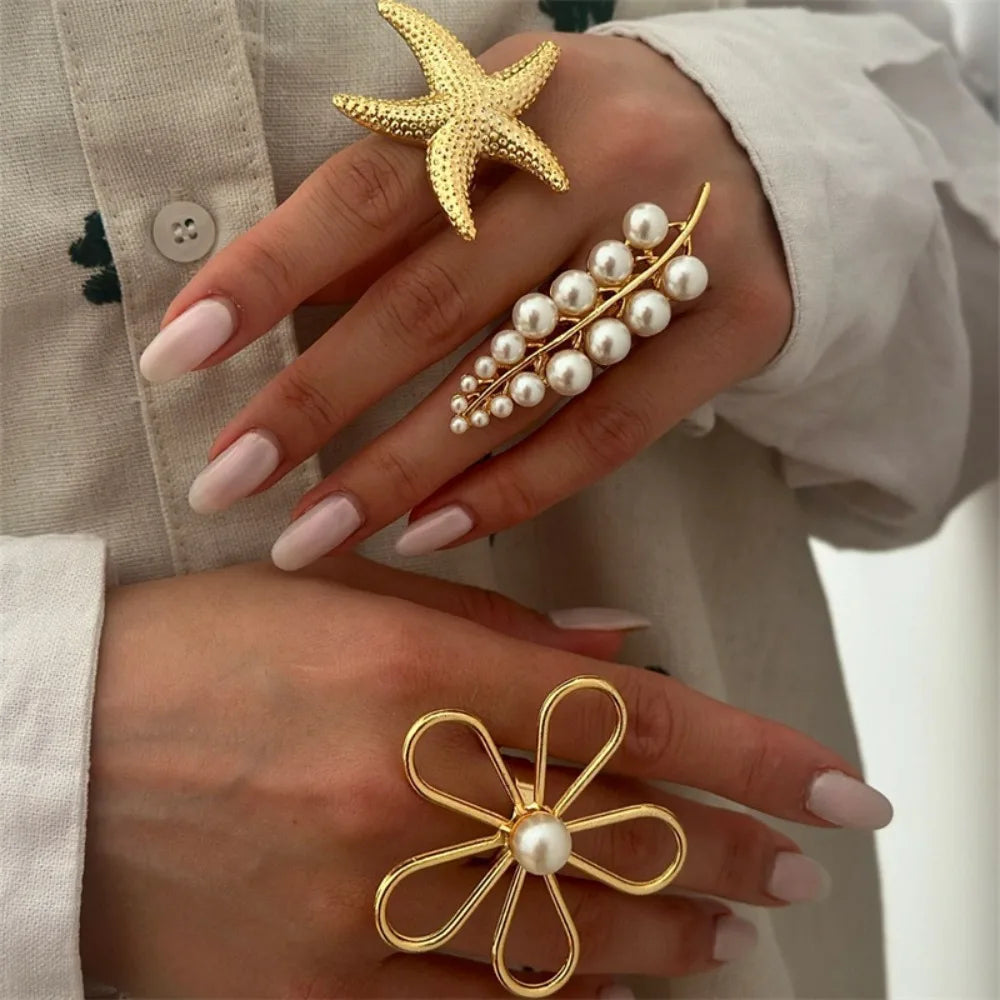 Gold starfish-shaped pearl ring with five looping petals and a central white pearl
