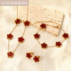 Clover jewelry set with red clover charms, gold-tone chain bracelet, necklace, and earrings
