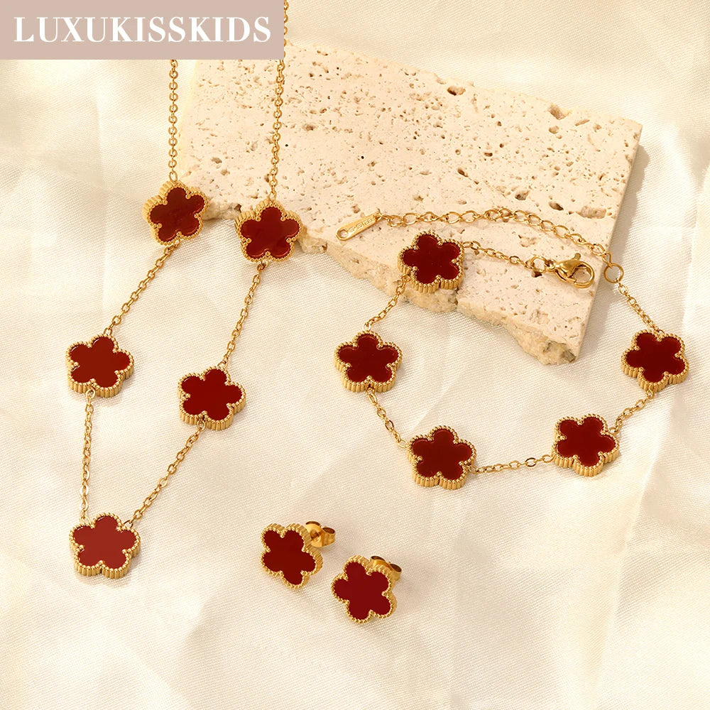 Clover jewelry set with red clover charms, gold-tone chain bracelet, necklace, and earrings