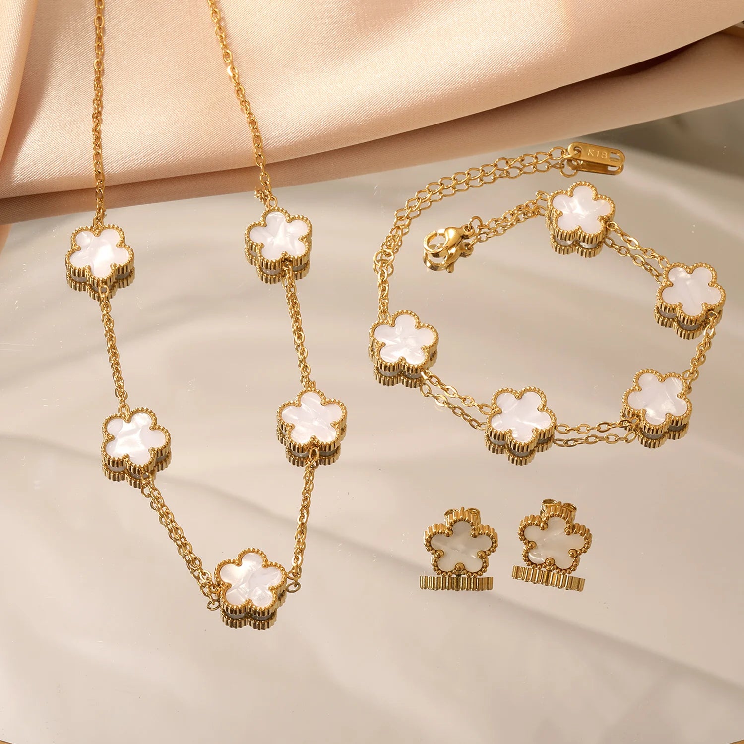 Gold-tone clover jewelry set with white enamel necklace and bracelet, plus stud earrings