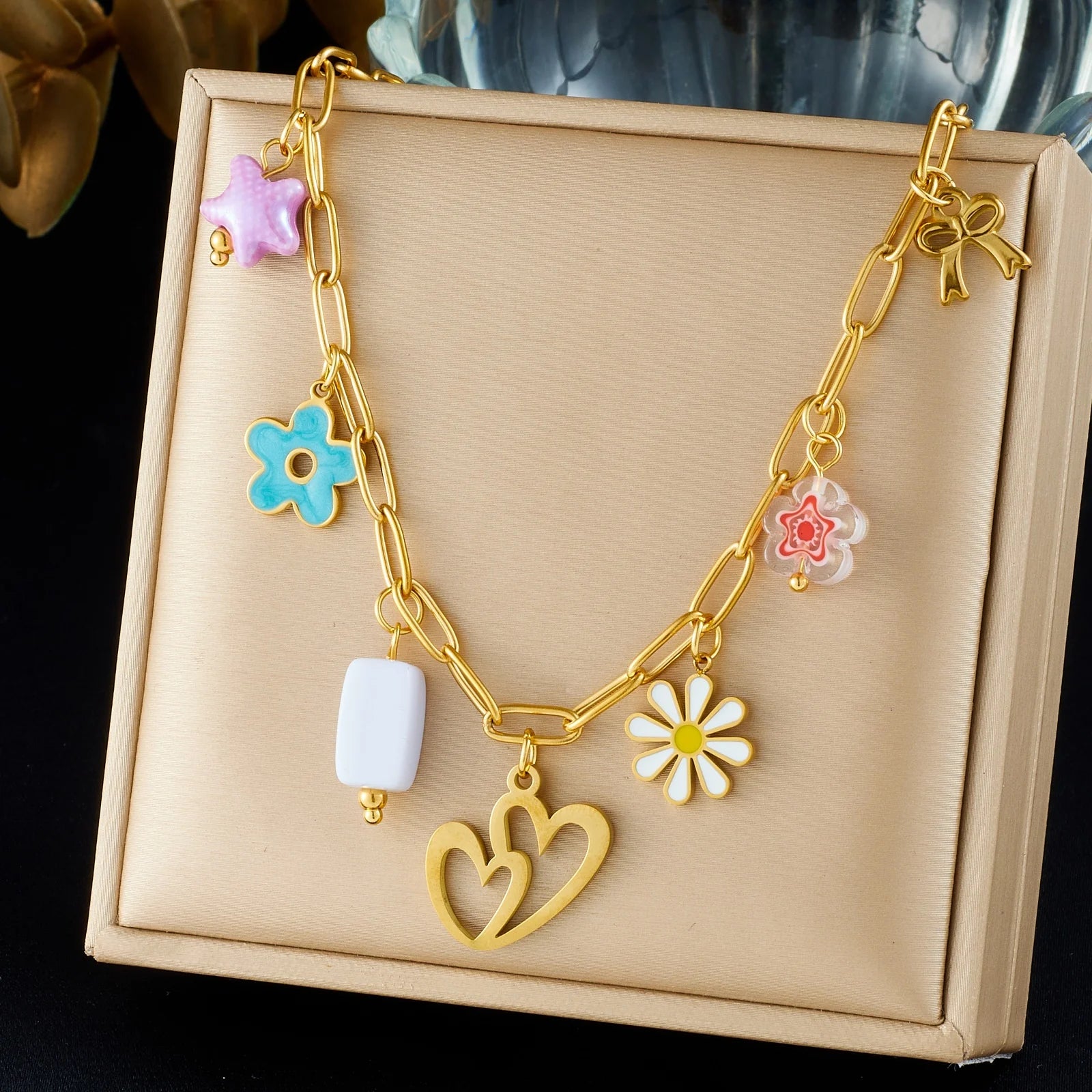 Gold enamel pendant necklace in gift box with heart, flower, and bow charms