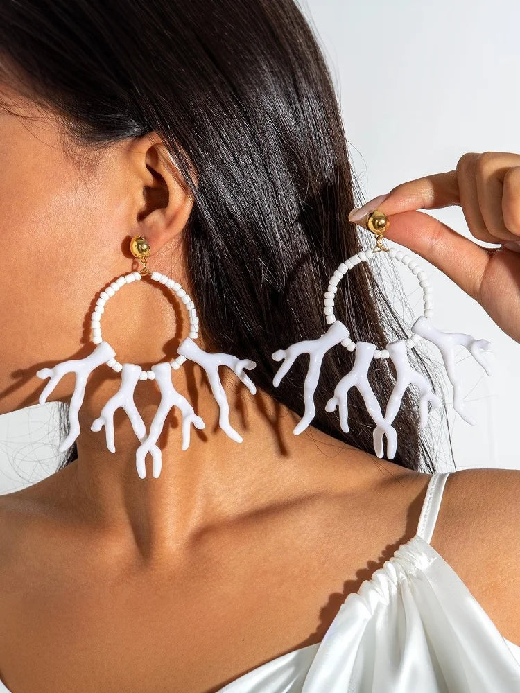 White acrylic drop earrings with gold-toned studs, hoop beads, and fringe drops