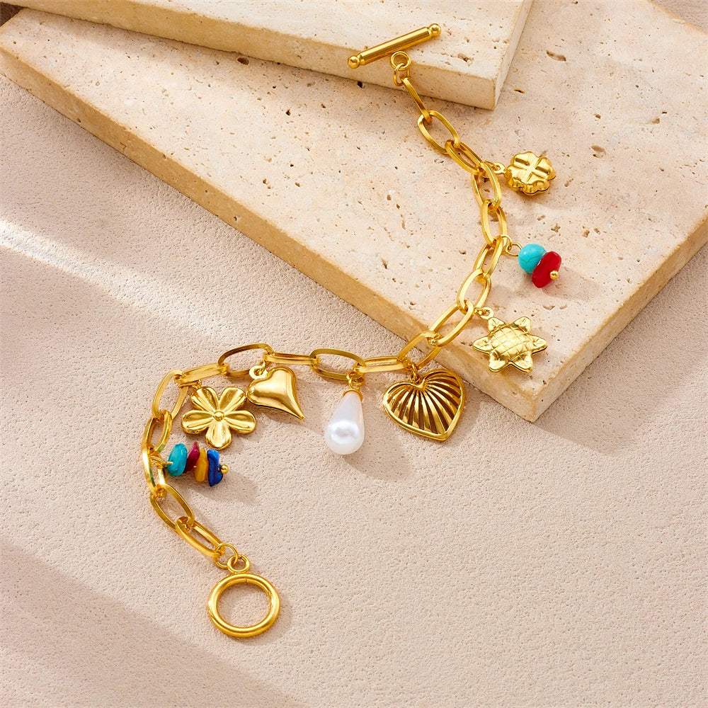 Gold-tone charm bracelet with heart, pearl and shell charms plus turquoise bead accents