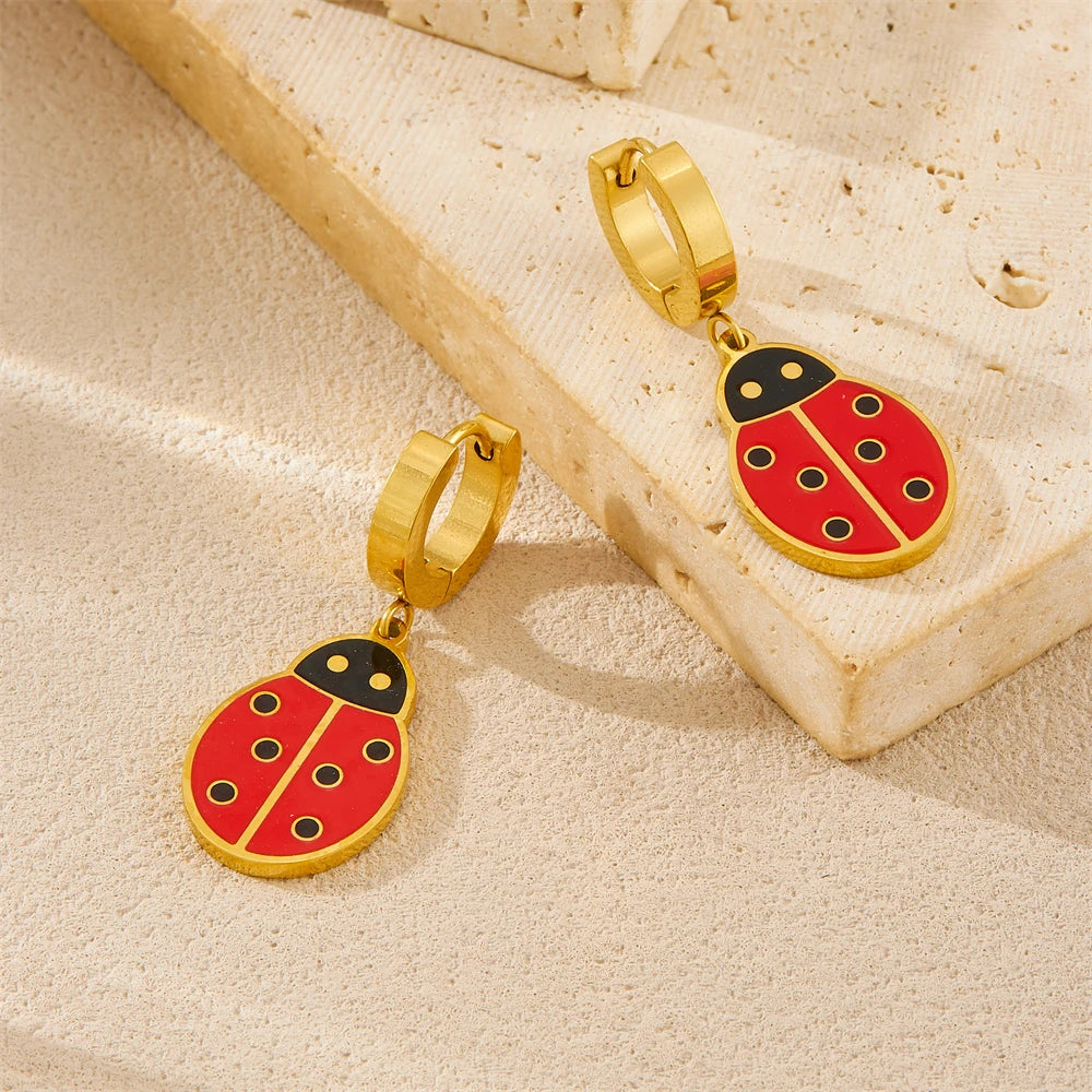 Gold-tone ladybug dangle hoop earrings with red enamel body and black details
