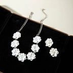 White flower necklace and stud earrings set on black display