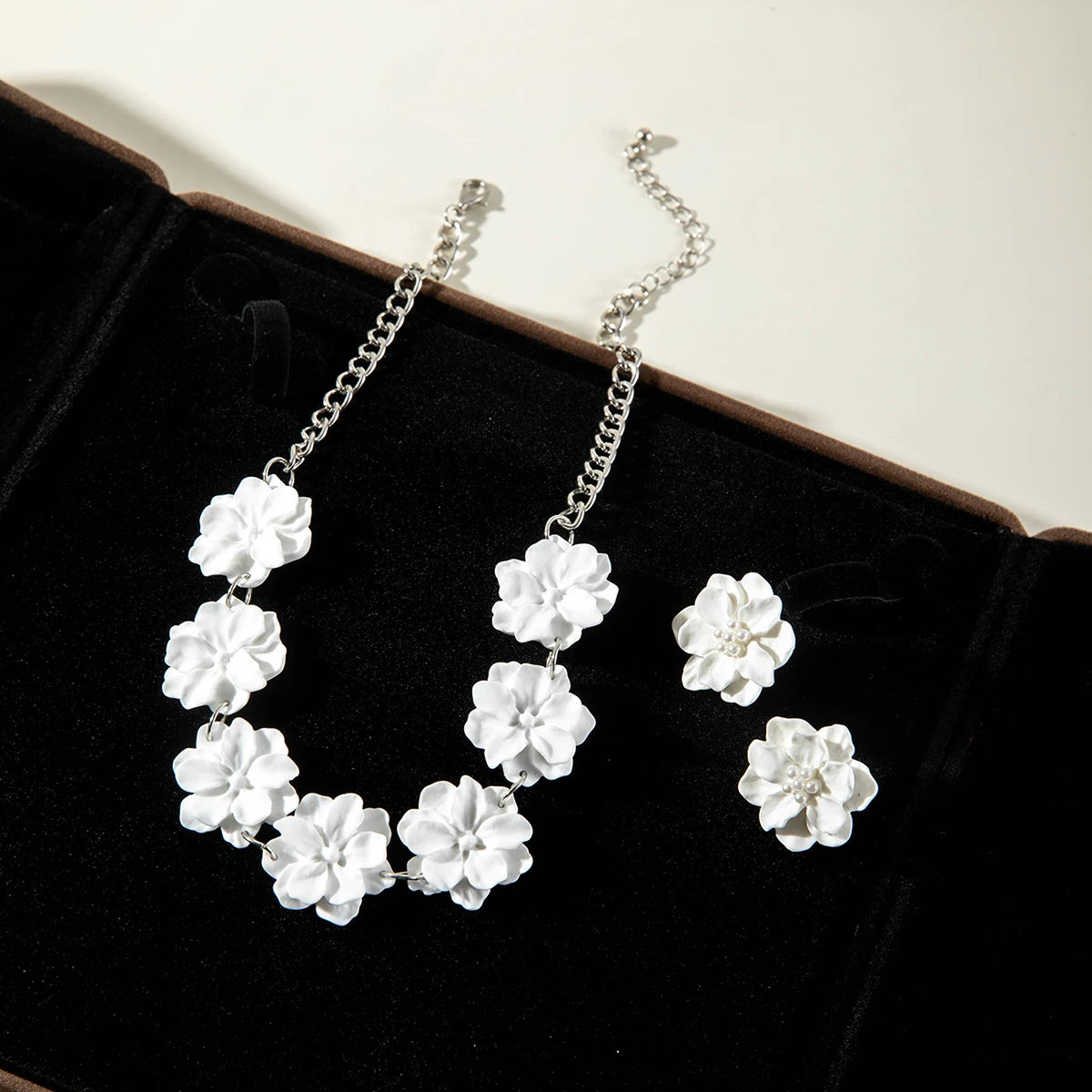 White flower necklace and stud earrings set on black display