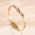 Gold plated evil-eye bangle with blue enamel ovals and rhinestone-accented links