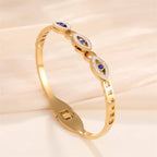 Gold plated evil-eye bangle with blue enamel ovals and rhinestone-accented links