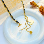 Gold-tone heart pendant necklace with black enamel heart and pearl plus gold ball