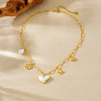 Gold-tone heart pendant necklace with pearl drop and butterfly and flower charms