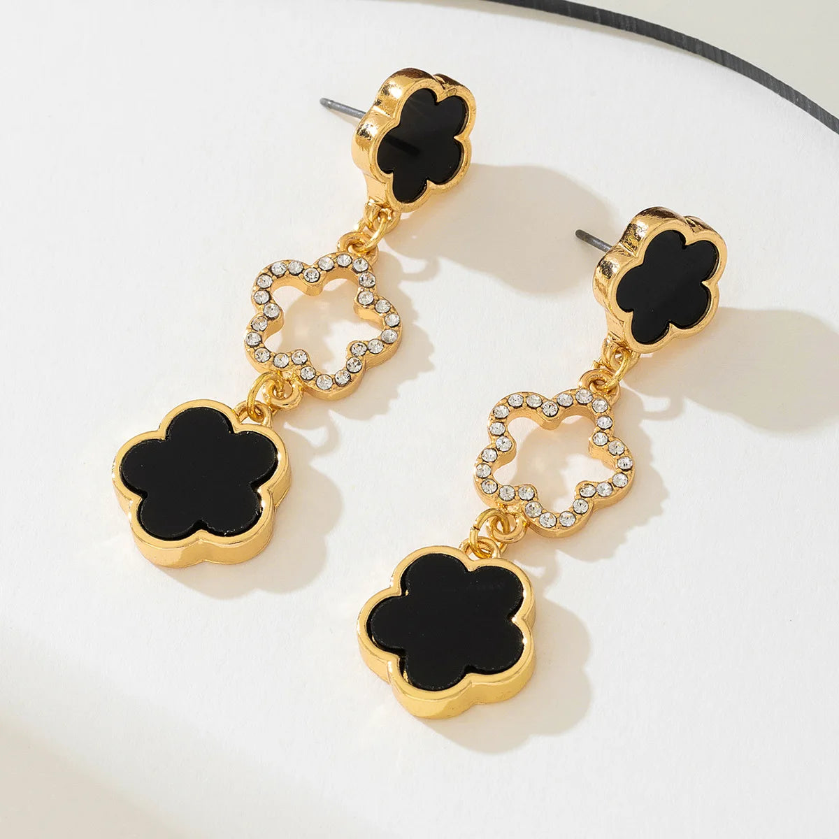 Gold-tone five-petal flower long drop earrings with black enamel and rhinestone ring centers
