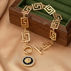 Gold embossed chain anklet with Greek-key links and round lion medallion charm