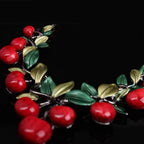 Cherry fruit necklace detail: red cherry beads and green leaf charms with silver-tone links