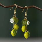 Lemon tassel drop earrings with yellow acrylic lemons, green leaves, and white flower details