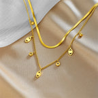 Gold-tone double-layer snake chain necklace with heart-shaped charm accents and small beads