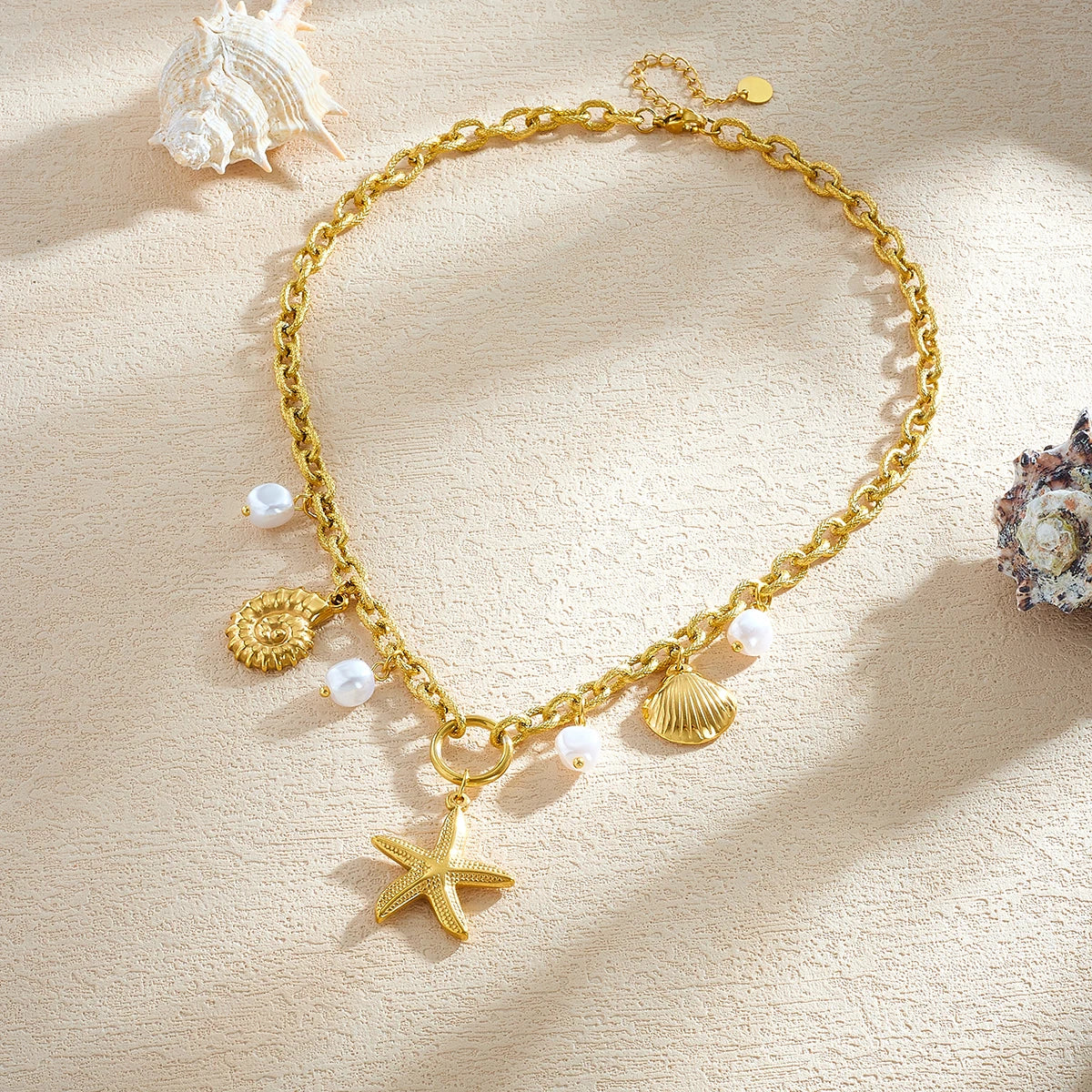 Gold-plated starfish charm necklace on display with shell and white pearl bead accents