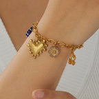 Gold-tone charm bracelet with blue accent heart charm, small flower charm, and bow charm