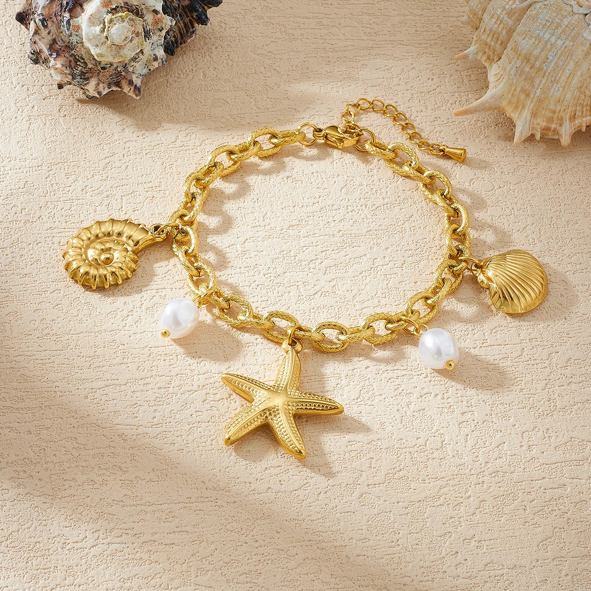 Gold-tone charm necklace with starfish, seashell charms, and white pearl beads