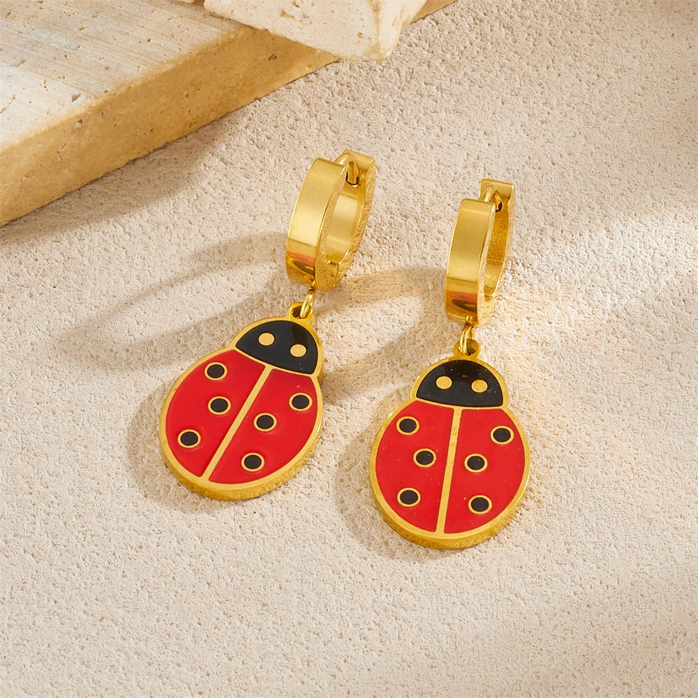 Gold-tone ladybug drop hoop earrings with red enamel, black wing lines, and gold backing