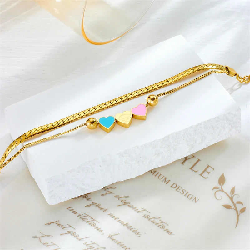 Gold heart charm necklace with blue and pink enamel hearts and small cream hearts