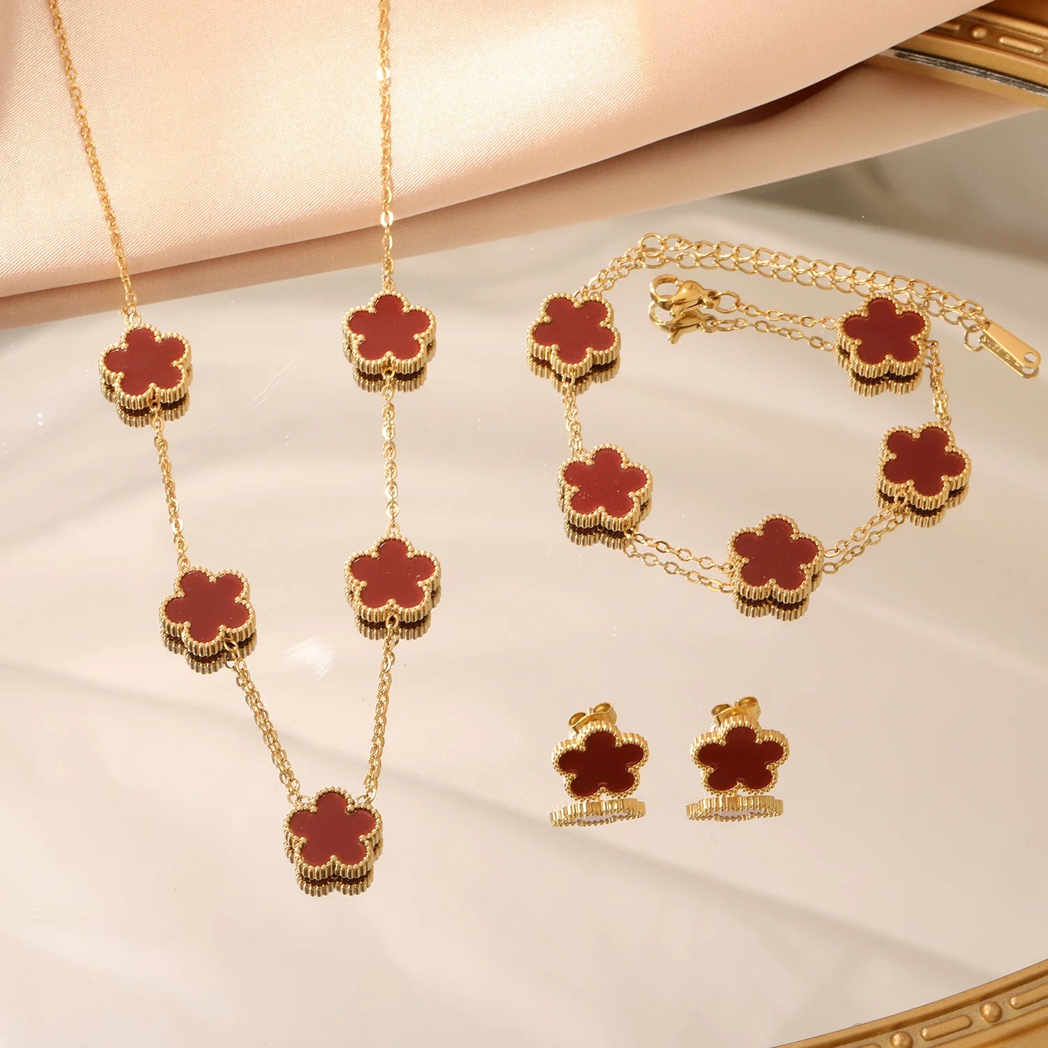 Gold-tone clover jewelry set with red enamel necklace, bracelet, and stud earrings