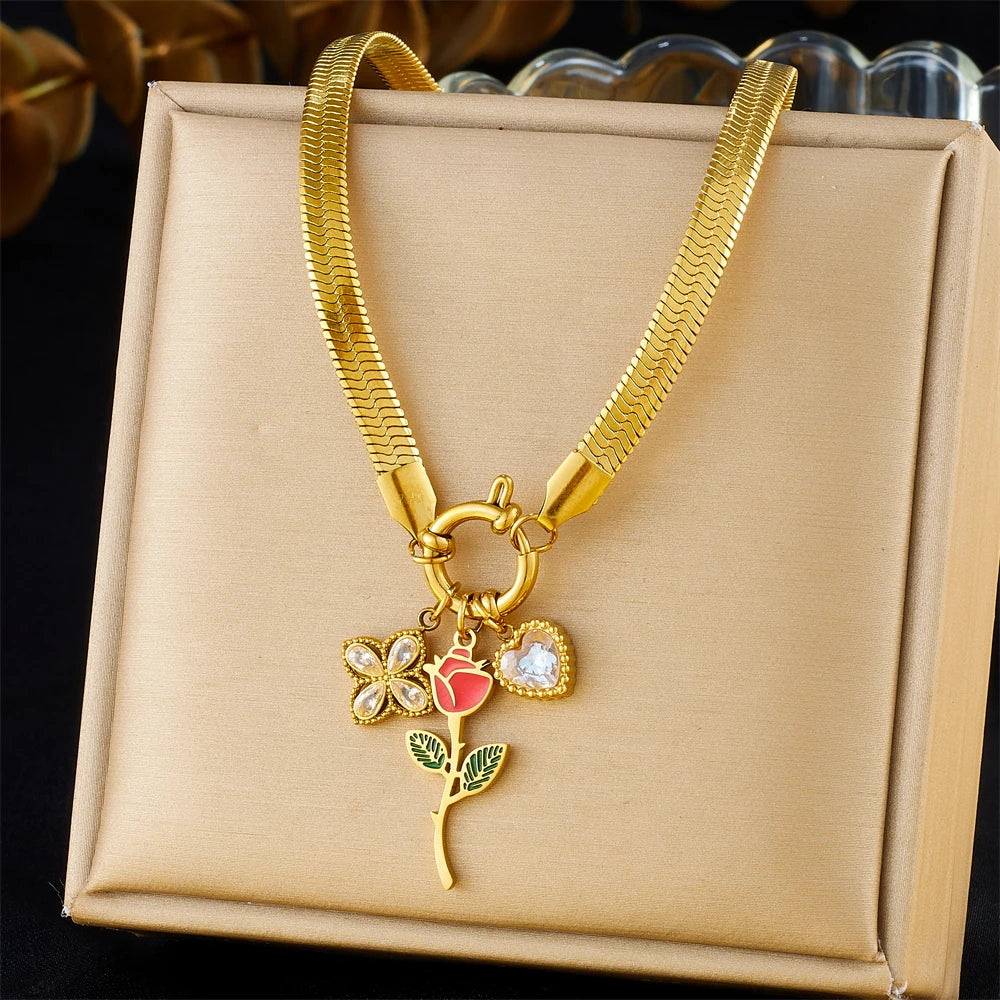 Gold-tone pendant necklace with rose, leaf, and red enamel charms in gift box