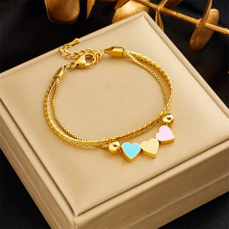 Gold heart charm bracelet with blue and pink enamel heart pendants