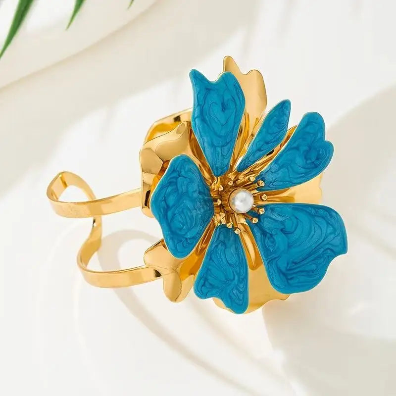 Flower cuff bangle bracelet with gold-tone band and blue enamel five-petal flower, pearl center.