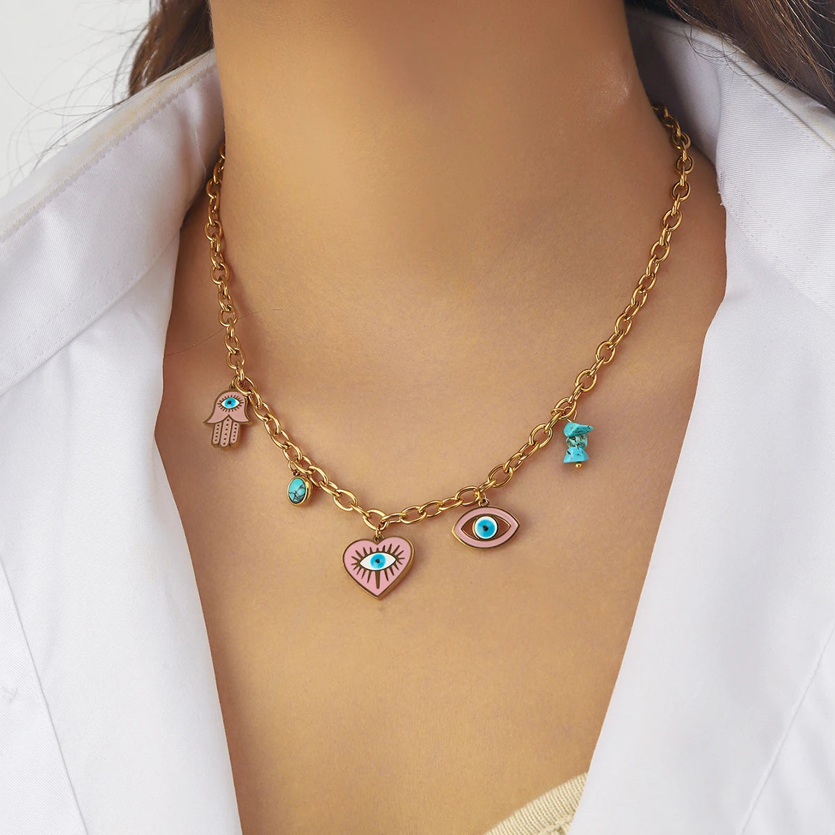 Gold-tone evil eye charm necklace with turquoise beads, hamsa hand, and heart pendants