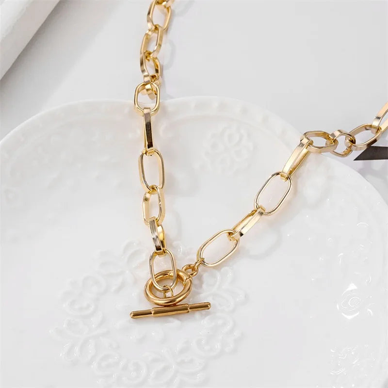 Gold-tone oval link chain collar necklace close-up with heart clasp and bar charm