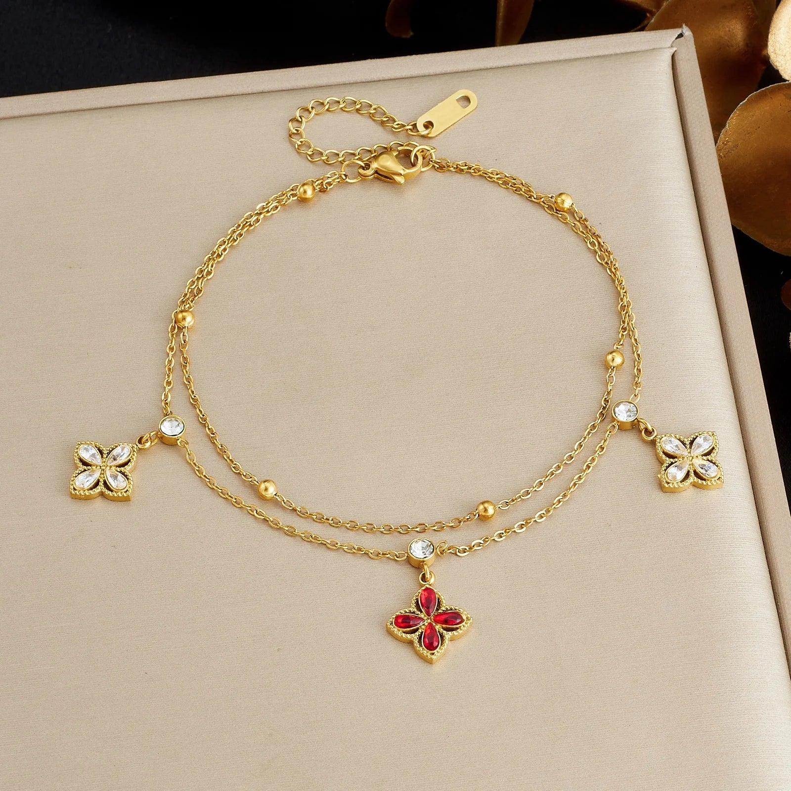 Gold-tone flower charm bracelet with red crystal pendant and white crystal flower details