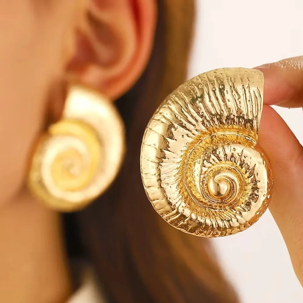 Gold-tone conch shell stud earring with textured ridges and spiral center
