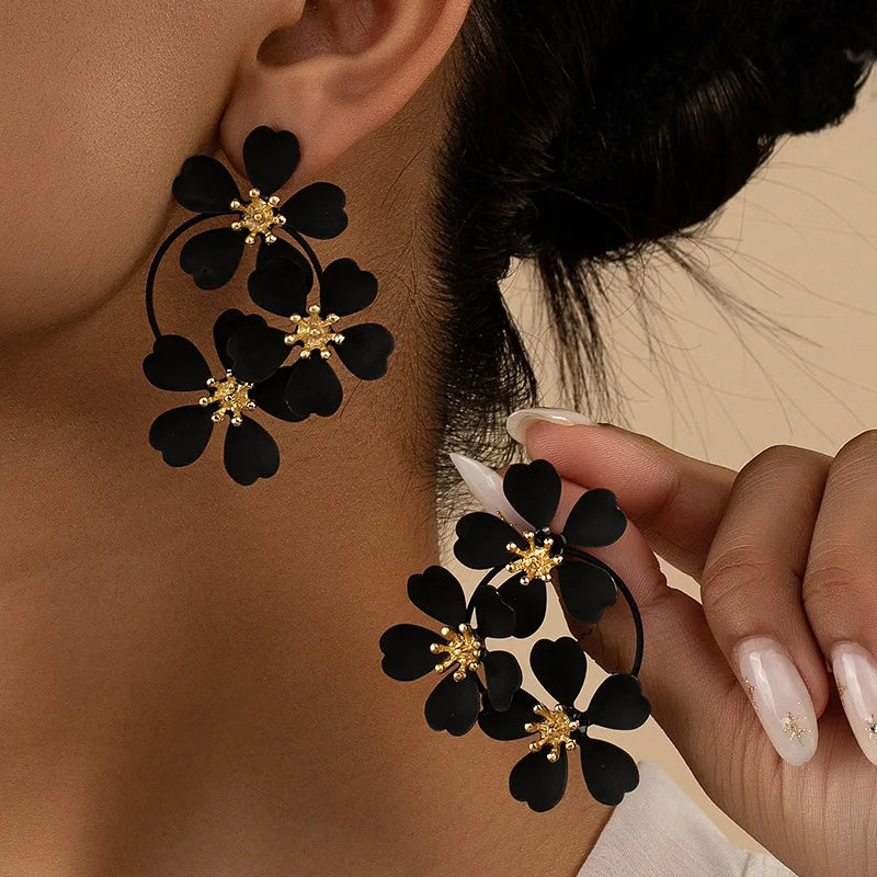 Flower dangle earrings with black five-petal flowers and gold-tone hoop loops