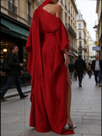 Red one-shoulder maxi gown in back view with draped sleeve and high slit