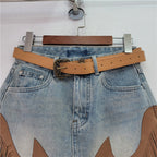 Light blue denim skirt with tan belt, ornate buckle, and fringe tassel hem
