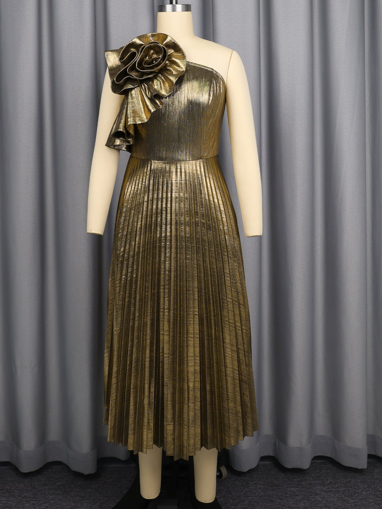Gold one-shoulder pleated midi dress on mannequin with floral applique at shoulder